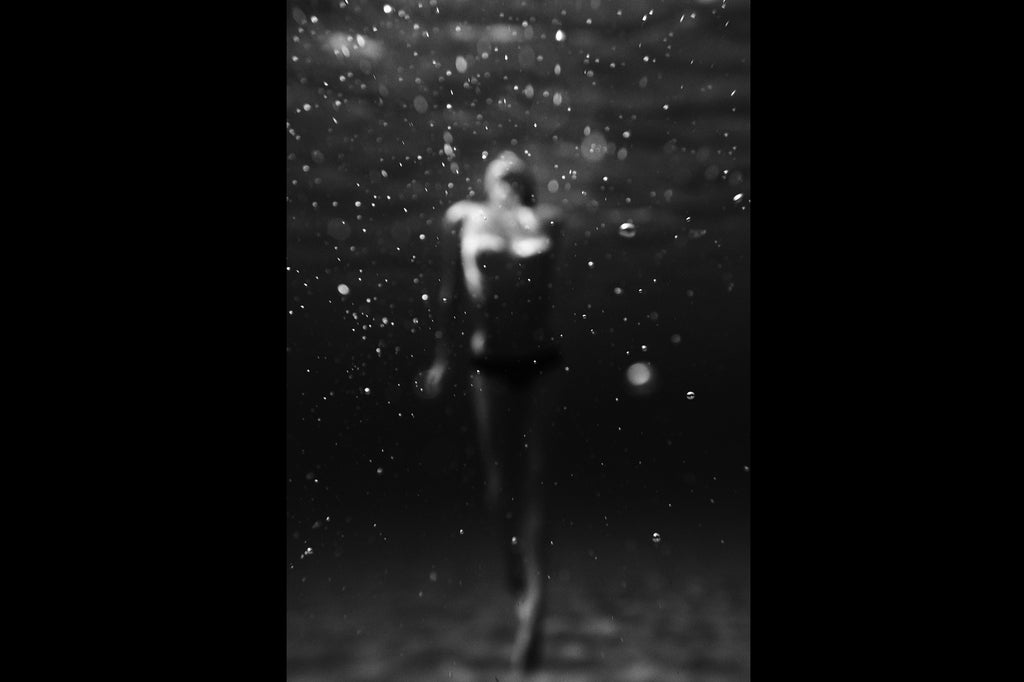 KaneSkennarphotographer-BW photo of unfocused woman swimming underwater with bubbles