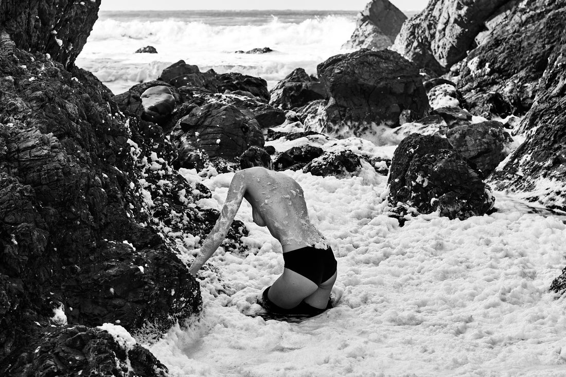 Kane Skennar photographer-Woman with back to camera standing in water and rocks bw.